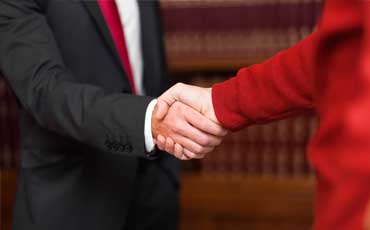 Lawer reassuring client by clasping his hands with his